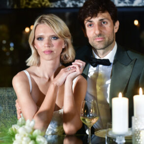 Couple seated at elegant table with candles.