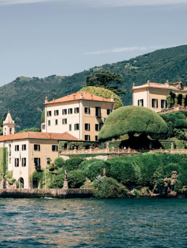 A large white building sitting on top of a lush green hillside