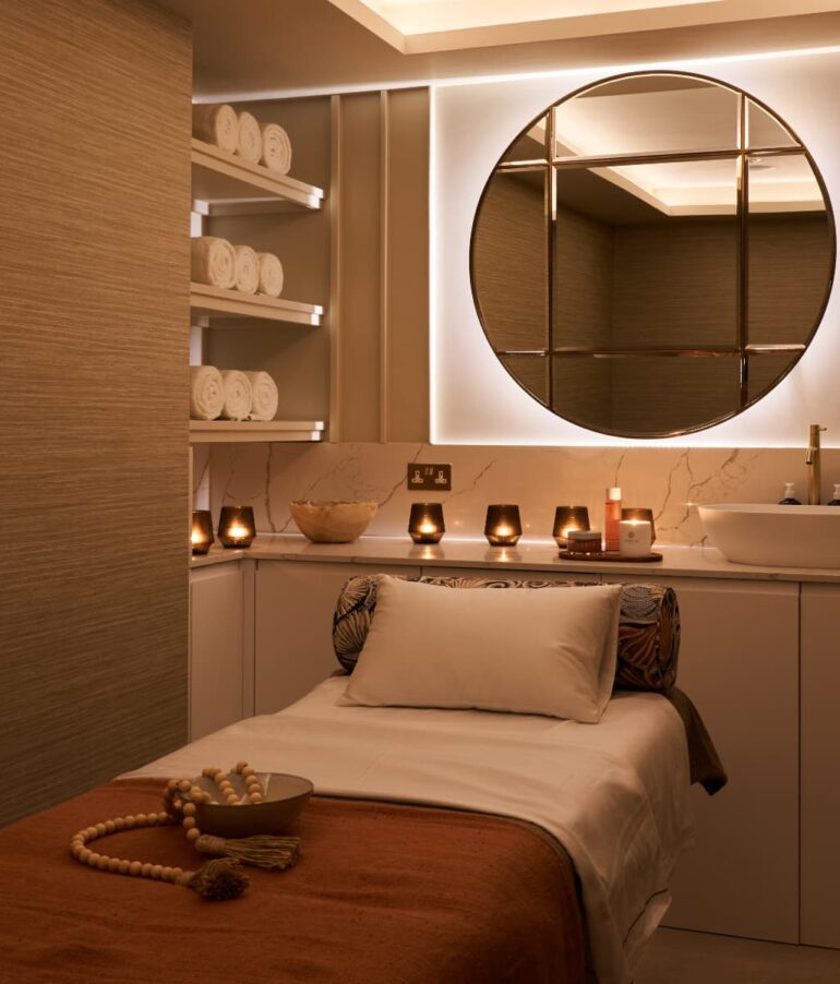 Cosy spa massage room with candles and towels.