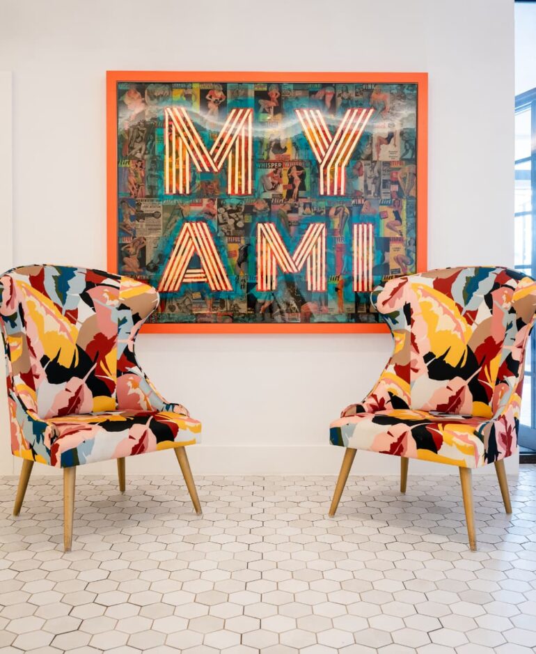 Colourful chairs and 'MY AMI' wall art in room.
