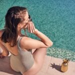 Woman reading by swimming pool, with pineapple tumbler.