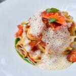 Gourmet pasta with sauce and foam garnish.
