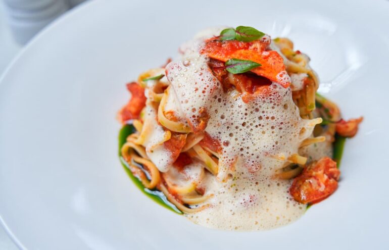Gourmet pasta with sauce and foam garnish.