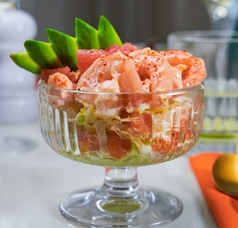 Classic prawn cocktail with avocado garnish in glass dish.