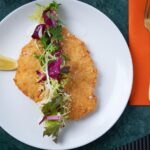 Breaded schnitzel with salad and lemon slice.