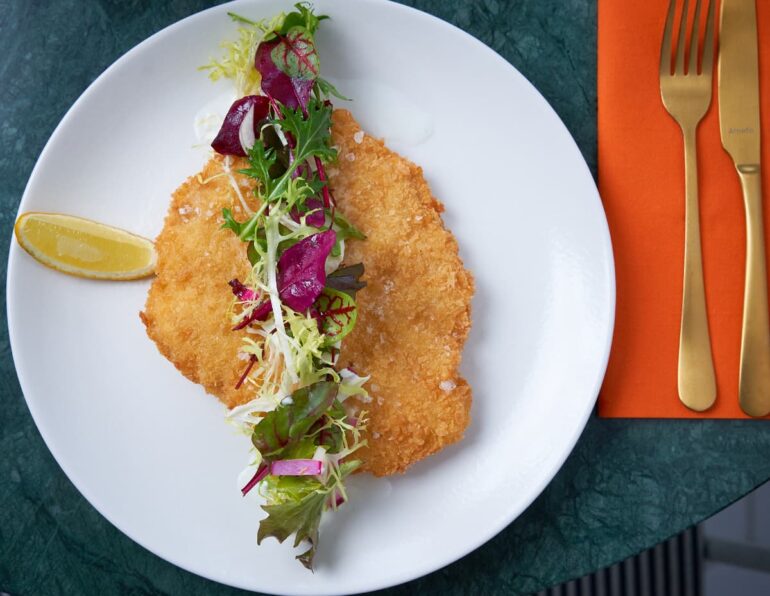 Breaded schnitzel with salad and lemon slice.