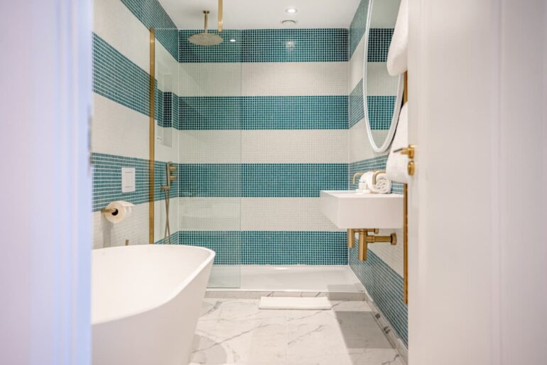 Modern bathroom with tub and blue tiles.