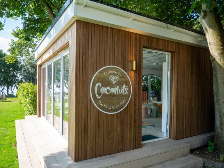 Modern wooden building, sign reads 'Welcome to Coconuts'.