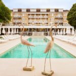 Luxury poolside with statues and loungers at hotel.