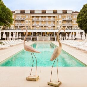 Luxury poolside with statues and loungers at hotel.