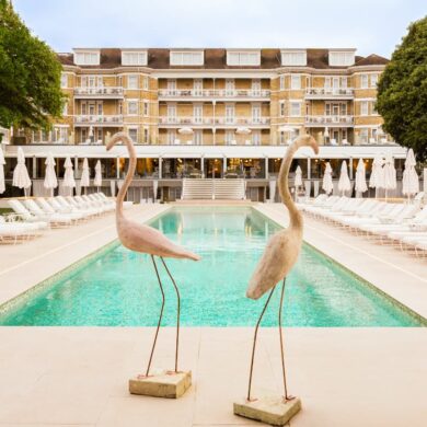 Luxury poolside with statues and loungers at hotel.