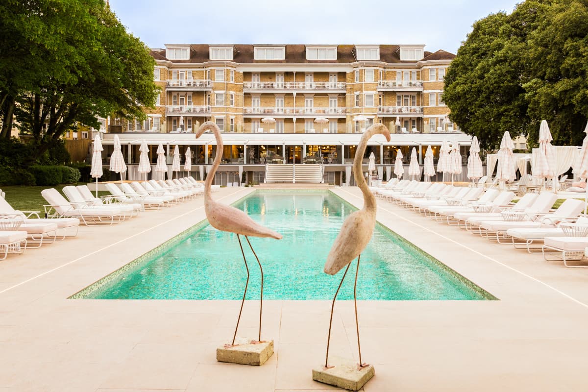 Luxury poolside with statues and loungers at hotel.