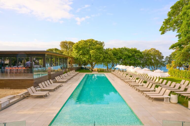 Resort pool with loungers and sea view.