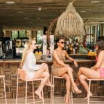 Three women chatting at an outdoor bar.