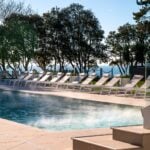 Outdoor pool with sun loungers and trees
