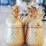 Gold pineapple-shaped drink containers on table