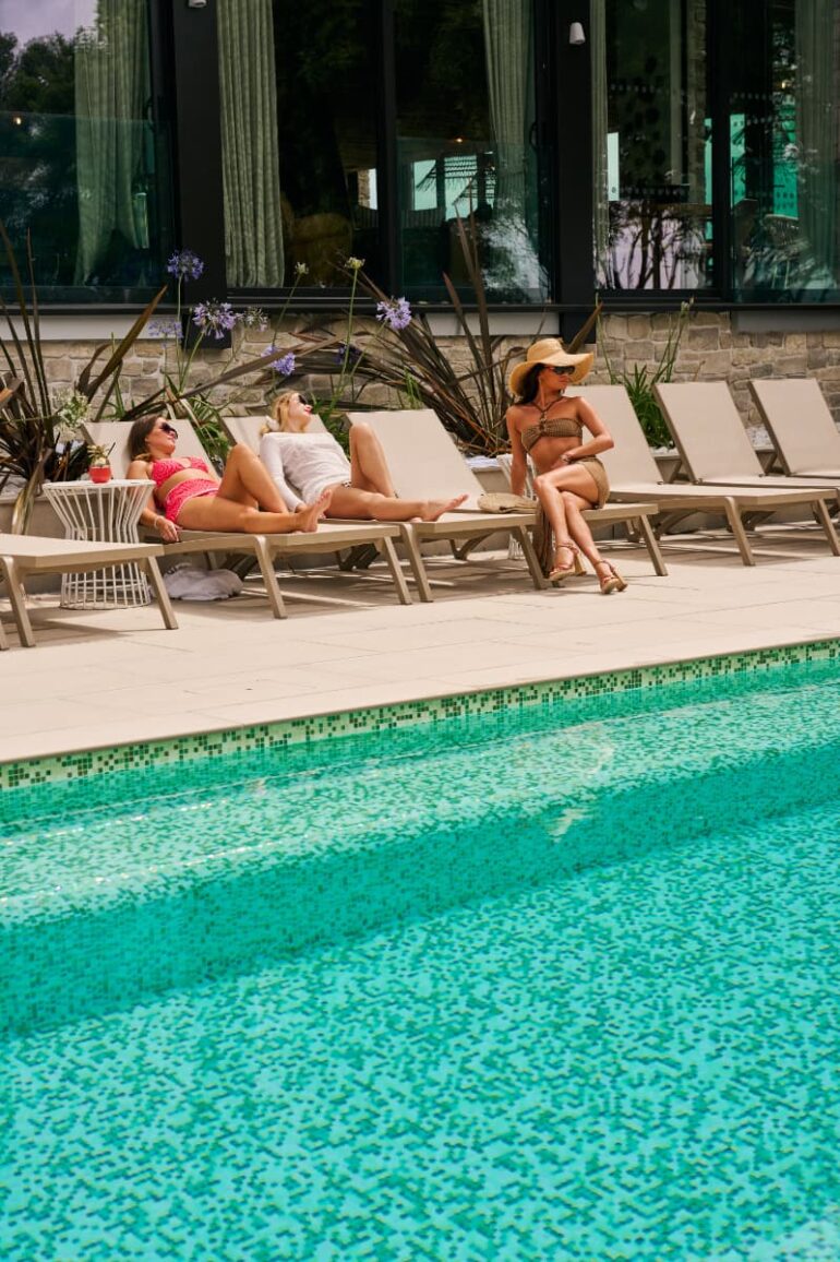 Women relaxing by outdoor swimming pool