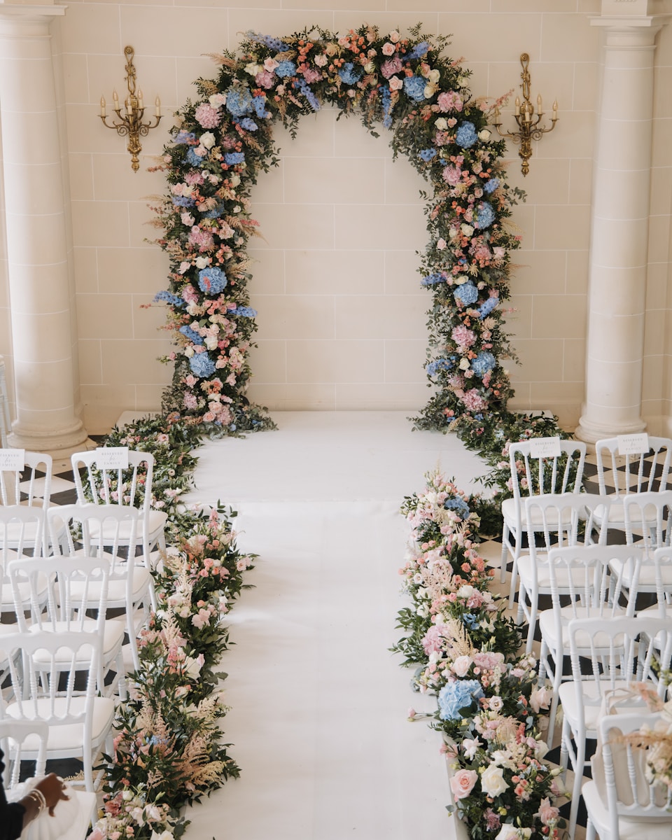 Floral archway with chairs set for a wedding ceremony.