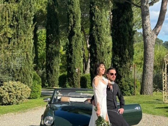 A stylish couple poses for a photo near a vintage car.