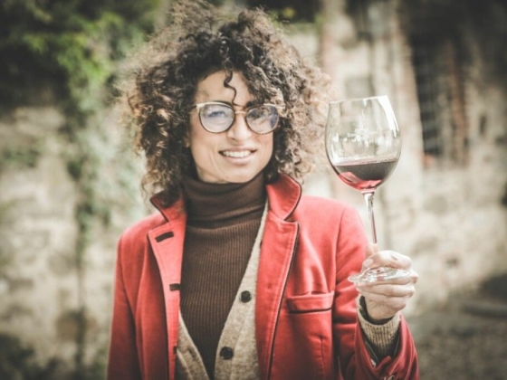 A stylish individual enjoying red wine outdoors.