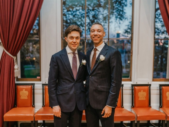 A celebratory moment captured with two grooms in formal attire.