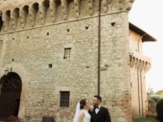 A couple in wedding attire in front of a castle-like structure.