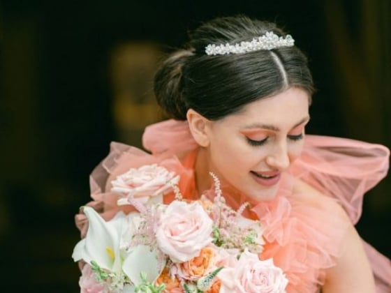 A joyful bride smiles while holding her floral bouquet.