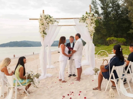 Couple exchanging vows on the beach at sunset.