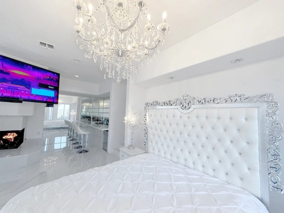 Stylish white bedroom featuring a large TV and bar area.