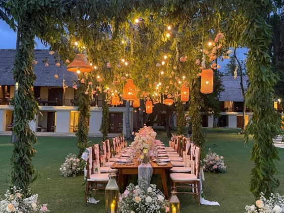 Elegant garden dinner table adorned with flowers and lights.