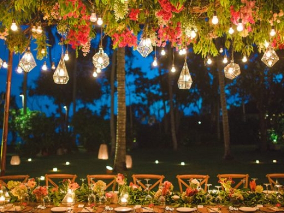 Beautifully arranged table under hanging lights and flowers.