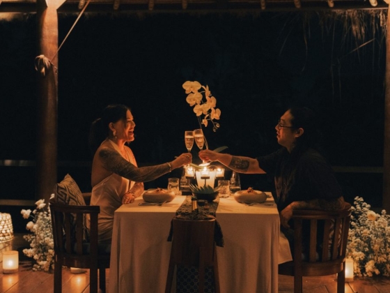 Couple toasting drinks in a cozy setting at night.