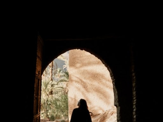 A person stands in a doorway, framed against a serene backdrop.