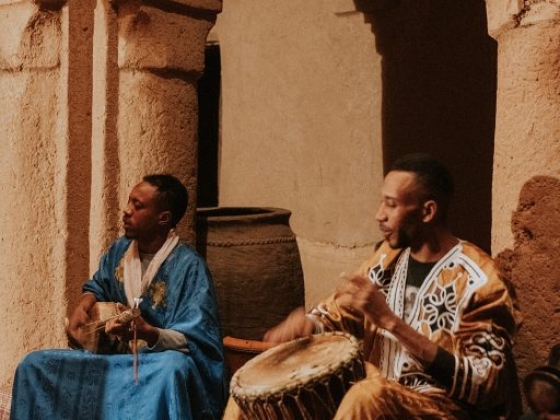 Musicians perform with drums and a lute in a cozy atmosphere.