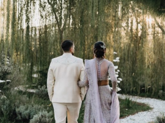 A couple in traditional attire strolls through a serene garden path.