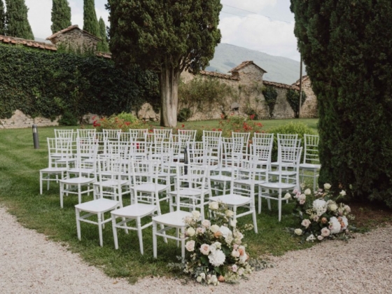 Chairs set up for a wedding ceremony in a scenic garden.