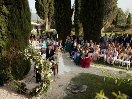 A couple exchanges vows surrounded by guests in a lush garden.