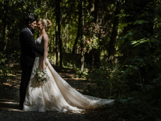 A couple embraces in a serene wooded setting.