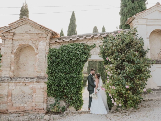 Couple stands together in a floral archway.