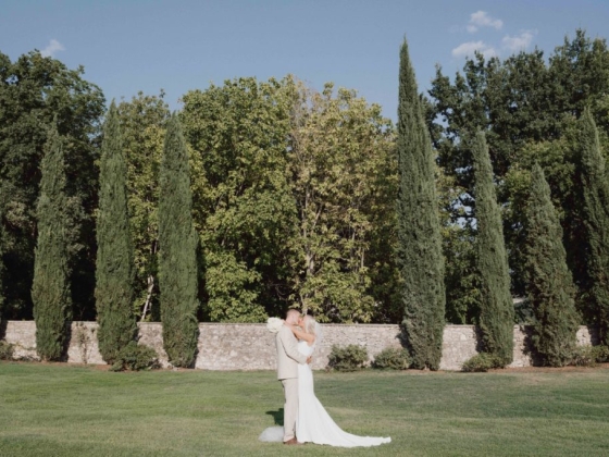 A couple embraces passionately in a green landscape.