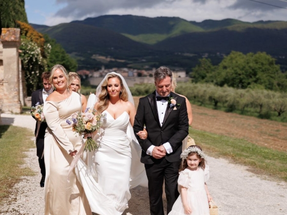 Bridal party in formal wear strolling outdoors.
