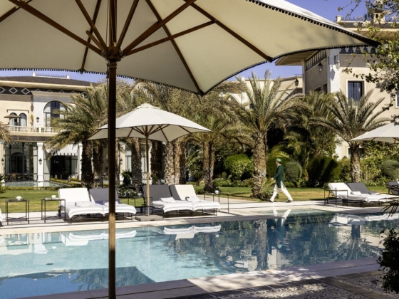 A serene villa pool scene with lounge chairs and palm trees.