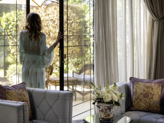 A serene interior with a woman gazing outside.