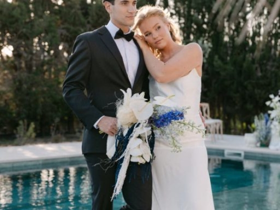 A couple dressed for a wedding by a serene pool.
