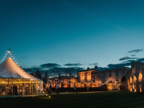 Twinkling lights decorate a tent and historic building.