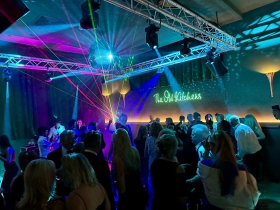 Dancers enjoying music under vibrant lights and a disco ball.