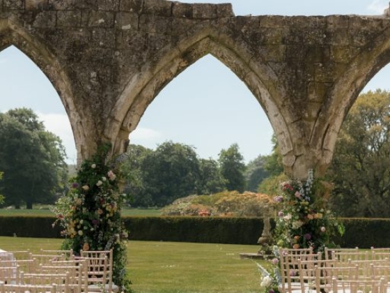 A beautiful outdoor wedding scene featuring a stone arch.