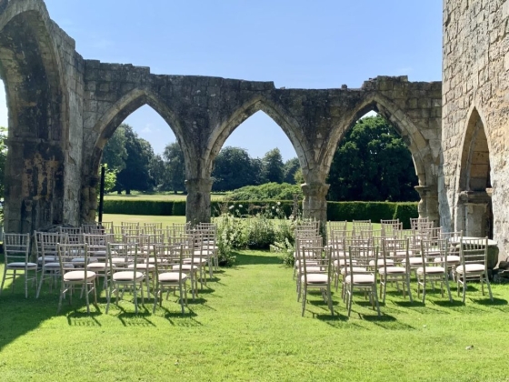 Chairs arranged for a ceremony among ruins and greenery.
