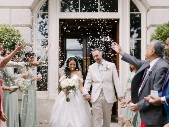 Newlyweds joyfully leaving the venue with guests celebrating.