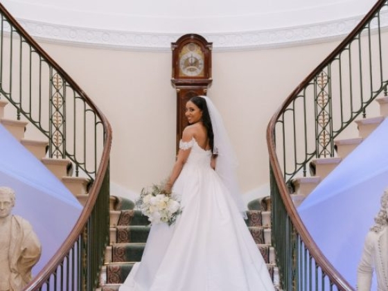 A bride holding a bouquet on a staircase.
